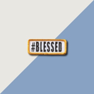Puede incluir: Un parche bordado amarillo y blanco con el texto "#BLESSED" en negro.