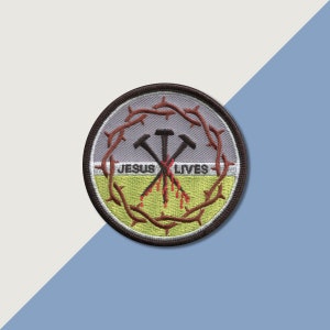 May include: A round, embroidered patch with a brown thorn crown, two crossed hammers, and the text "JESUS LIVES" in red and black lettering. The patch has a gray background with a yellow border.