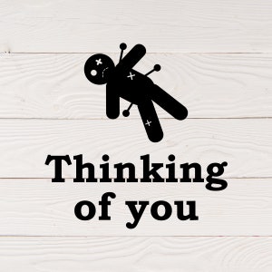May include: A black voodoo doll with pins sticking out of it, lying on a white wooden background. The text "Thinking of you" is written below the doll.