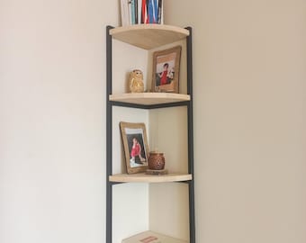 Puede incluir: Una estantería de esquina con tres estantes de madera y metal negro. Los estantes son curvos y tienen una variedad de artículos, incluyendo libros, fotos y objetos decorativos.