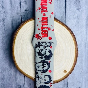 May include: Gray silicone watch band with a red "Serial Killer" text and black and white silhouette images of people.