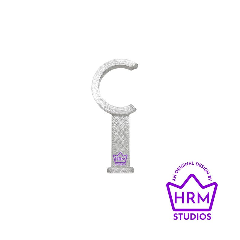 Puede incluir: Un soporte plateado para barra de cortina con una parte superior curva y una base rectangular. La base presenta un logotipo p&uacute;rpura con el texto "HRM STUDIOS" y las palabras "AN ORIGINAL DESIGN BY".