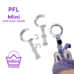 Puede incluir: Llaveros PFL Mini de plástico transparente con cuentas de letras, un llavero plateado y un accesorio de felpa morada. El texto "PFL Mini" y "HRM Studios" son visibles.