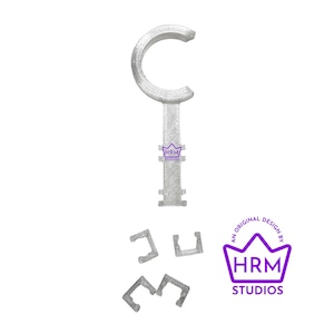 Puede incluir: Un objeto en forma de llave, impreso en 3D, de color gris claro, con una parte superior curvada y un mango texturizado. Tambi&eacute;n hay tres piezas m&aacute;s peque&ntilde;as en forma de C a juego. La imagen incluye un logotipo p&uacute;rpura que dice "HRM STUDIOS".
