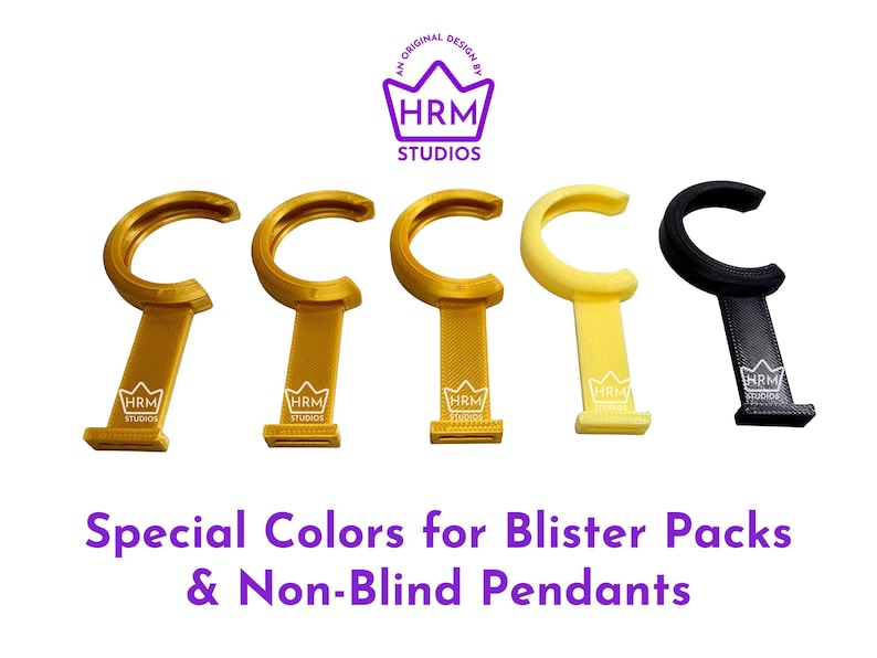Puede incluir: Cinco colgantes para bl&iacute;ster en oro, amarillo y negro. Cada colgante tiene una parte superior curvada y una base rectangular con el logotipo "HRM Studios". El texto en la parte inferior dice "Special Colors for Blister Packs & Non-Blind Pendants."