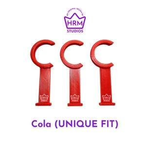 May include: Three red, C-shaped bottle openers with a unique fit design. Each opener has a long, rectangular handle with the "HRM Studios" logo. The text "Cola (UNIQUE FIT)" is displayed below the openers.