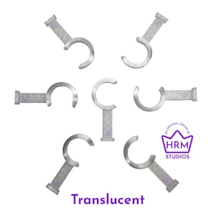 Puede incluir: Ganchos transl&uacute;cidos plateados con un dise&ntilde;o curvo, dispuestos sobre un fondo blanco. Cada gancho tiene una base rectangular con un logotipo de corona. La imagen tambi&eacute;n incluye el texto "Translucent" y un logotipo que dice "HRM Studios".