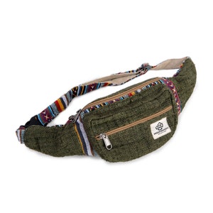 May include: A green canvas fanny pack with a zippered pocket and a woven strap with colorful geometric patterns. The bag has a brown leather patch with the text "FREAKMANJOU" in white.