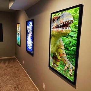 May include: A framed print of a green and yellow dinosaur with a black frame. The dinosaur is in a jungle setting with green leaves.