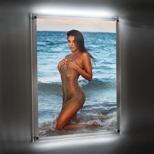 May include: A woman in a chainmail-like dress poses on a beach with the ocean in the background.