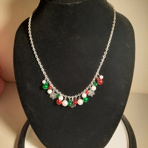 May include: A silver chain necklace with red, green, and white beads and snowflake charms.