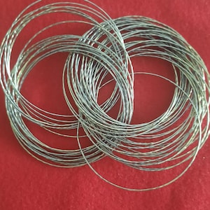 May include: A stack of silver-colored metal rings, each with a textured surface. The rings are arranged in a circular pattern, with the top ring slightly offset from the others.