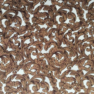 May include: A close-up of fabric featuring a repeating pattern of brown, stylized leaves and swirls on a white backdrop. The design has a vintage, ornate aesthetic, similar to classic wallpaper or upholstery.