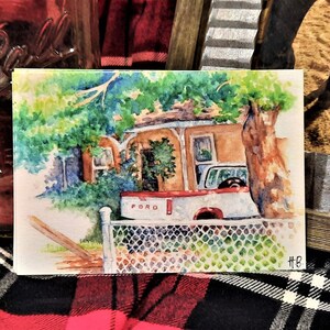 Könnte beinhalten: Aquarellgemälde eines Hauses mit einem roten LKW davor. Der LKW hat den Schriftzug "FORD" auf der Rückseite. Das Haus ist braun mit einem grünen Busch davor. Auf der rechten Seite des Gemäldes befindet sich ein Baum.