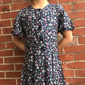 May include: A blue and white floral print dress with a button-up front and short sleeves.
