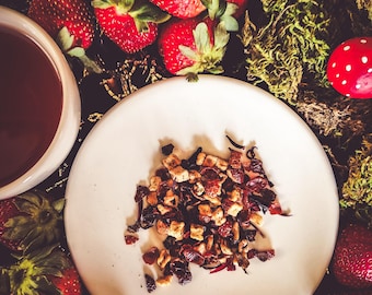 May include: A white ceramic plate with a small pile of dried fruit and flower tea. The plate is surrounded by fresh strawberries on a dark background.