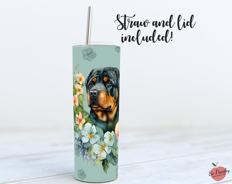 May include: A stainless steel tumbler with a floral design and a Rottweiler dog's head. The tumbler is teal blue with white and pink flowers. The text "Straw and lid included!" is at the top of the image.
