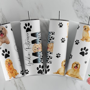 May include: Four white tumblers with black paw prints and golden retriever dog illustrations. The tumbler on the left has the text "Golden Retriever Mom".