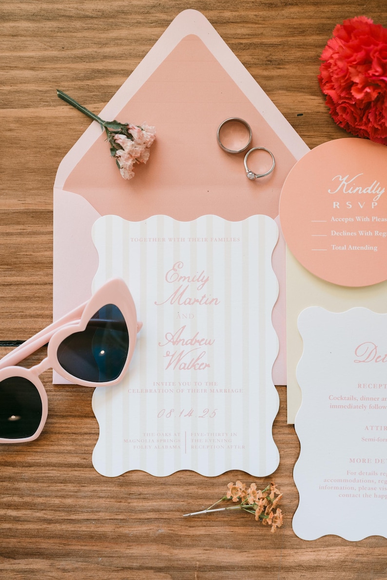 May include: A wedding invitation suite with a pink and white color scheme. The invitation features the names "Emily Martin and Andrew Walker" and the date "08.14.25". Heart-shaped sunglasses and wedding rings are also present.