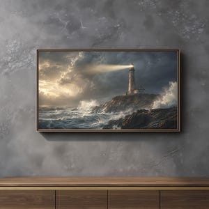 May include: A rectangular framed wall art print depicting a lighthouse on a rocky cliffside during a storm. The scene features dark, turbulent ocean waves crashing against the shore, a bright beam of light from the lighthouse, and cloudy skies.