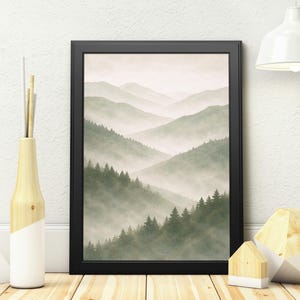 May include: A framed print depicting a tranquil mountain scene with layers of misty green hills and evergreen trees. The artwork is in a black frame, displayed on a wooden floor, with decorative items nearby.