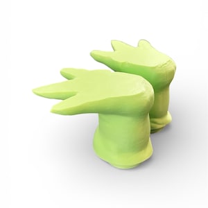 May include: Two light green, abstract, hand-shaped decorative objects. Each has a rounded base and three finger-like extensions. The objects are set against a white background, with soft shadows suggesting a three-dimensional form.