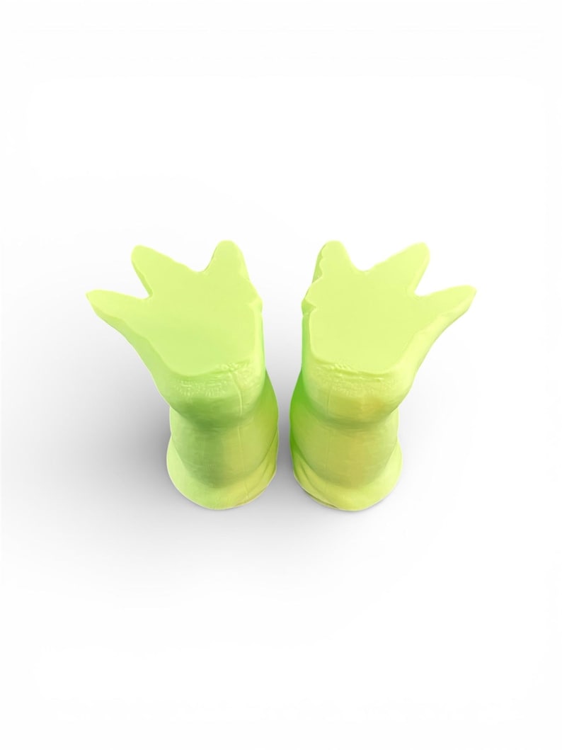 May include: Two lime green, foot-shaped ear plugs. The ear plugs are made of a soft material and have a three-pronged design. The ear plugs are designed to fit comfortably in the ear canal.