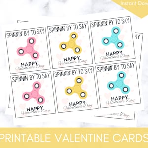 May include: Printable Valentine's Day cards featuring a colorful fidget spinner design with the text "SPINNIN' BY TO SAY" and "HAPPY Valentine's Day".