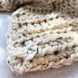 May include: Close-up of a white and black chunky knit blanket with a textured weave.