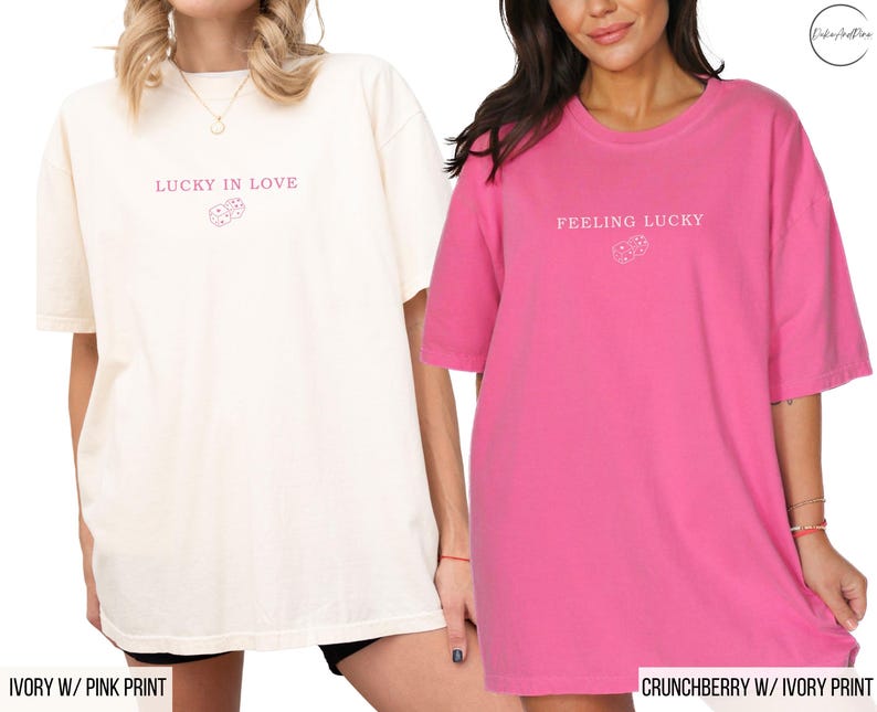 May include: Two oversized t-shirts, one ivory and one pink, with short sleeves. The ivory shirt has the text "LUCKY IN LOVE" and a dice graphic in pink. The pink shirt has the text "FEELING LUCKY" and a dice graphic in ivory.