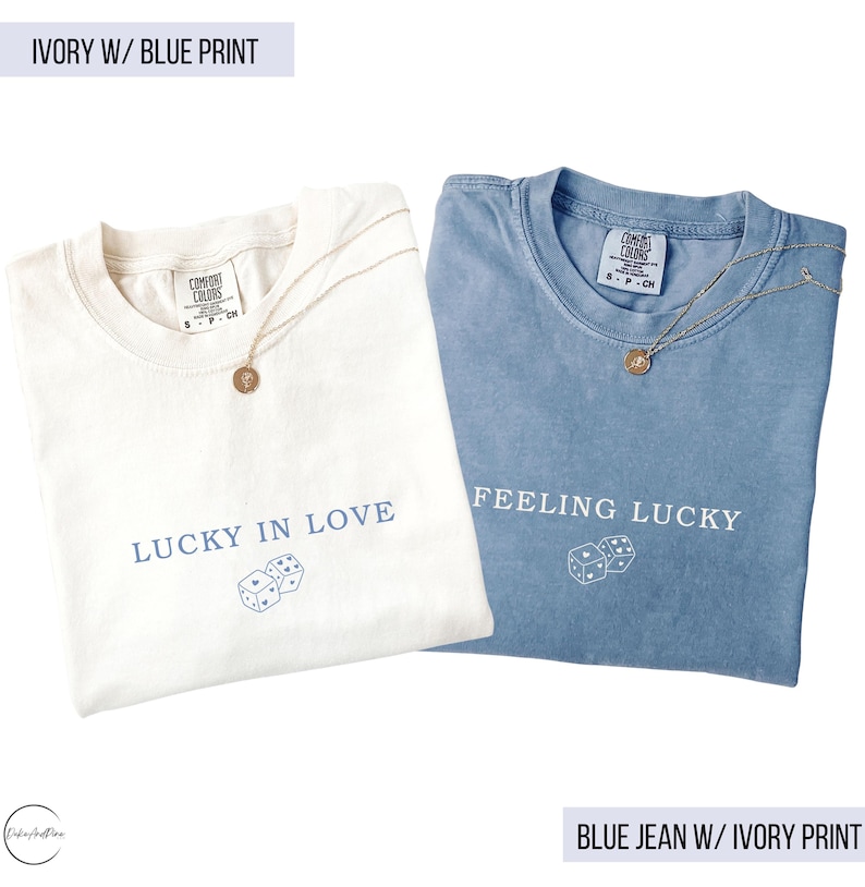 May include: Two t-shirts, one ivory and one blue, with gold necklaces. The ivory shirt says "LUCKY IN LOVE" with dice graphics. The blue shirt says "FEELING LUCKY" with dice graphics. Both shirts are Comfort Colors brand.