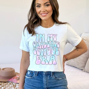 May include: White t-shirt with a tie-dye effect graphic that says "In My Graduate School Era".