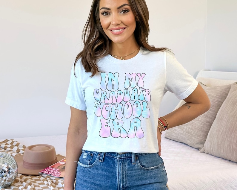 May include: White t-shirt with a tie-dye effect graphic that says "In My Graduate School Era".