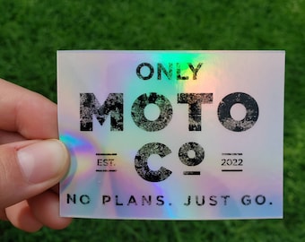 Op de afbeelding: Holografische sticker met de tekst "ONLY MOTO CO" in een verweerde lettertype. Onder het logo staan de woorden "EST. 2022" en de zin "NO PLANS. JUST GO."