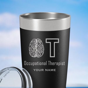 May include: Black stainless steel tumbler with a white design of a brain and the letter T. The text "Occupational Therapist" and "YOUR NAME" are also included in the design.