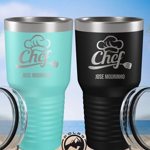 May include: Two stainless steel tumblers with lids. The tumblers are black and turquoise blue. Both tumblers have a silver chef hat and spatula design with the text "Chef" and "JOSE MOURINHO".