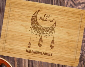 May include: A wooden cutting board with an engraved design of a crescent moon with a mandala pattern and the words "Eid Mubarak" and "The Brown Family".