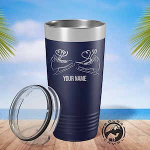 May include: Navy blue insulated tumbler with a silver rim and a clear lid. The tumbler features a white graphic of ice skates with heart-shaped laces and the text "YOUR NAME". The Polar Camel logo is visible.
