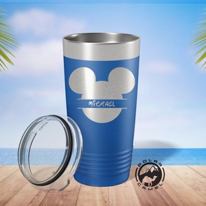 May include: A blue stainless steel tumbler with a Mickey Mouse silhouette and the name "MICHAEL" in a split font. The tumbler has a clear lid and is sitting on a wooden surface.