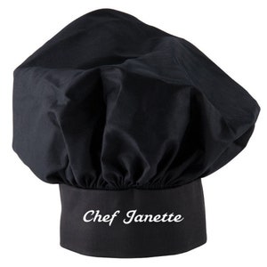Puede incluir: Sombrero de chef negro con el nombre "Chef Janette" bordado en blanco en la banda.