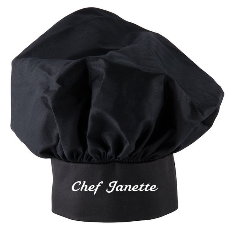 Puede incluir: Sombrero de chef negro con el nombre "Chef Janette" bordado en blanco en la banda.