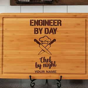May include: A rectangular bamboo cutting board with a juice groove, featuring a laser-engraved design of a chef hat and two crossed knives. The text reads ENGINEER BY DAY, Chef by night, and YOUR NAME in a mix of block and script fonts.