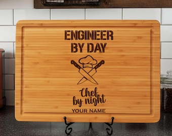 May include: A rectangular bamboo cutting board with a juice groove, featuring a laser-engraved design of a chef hat and two crossed knives. The text reads ENGINEER BY DAY, Chef by night, and YOUR NAME in a mix of block and script fonts.