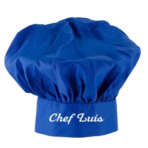 Puede incluir: Un gorro de chef azul con el nombre "Chef Luis" bordado en blanco en la parte delantera.