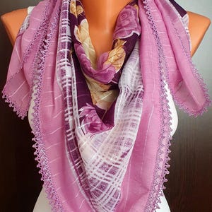 May include: A pink and purple floral patterned scarf with a crocheted trim. The scarf is draped over a white mannequin.