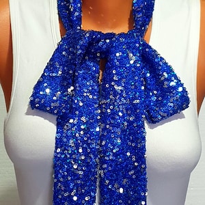 May include: A blue sequined bow tie. The bow tie is made of small, iridescent sequins and is tied in a classic bow shape.