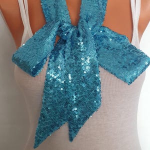 May include: A turquoise blue sequined scarf tied in a bow around a mannequin's neck.