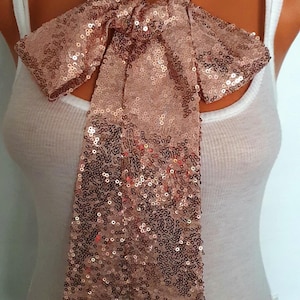 May include: A rose gold sequined bow tie. The bow tie is made of small, shimmering sequins and is tied in a classic bow shape.