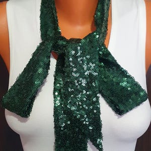 May include: A dark green sequined scarf tied in a bow around a mannequin's neck.