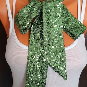 May include: A green sequined scarf tied in a bow around a mannequin's neck.